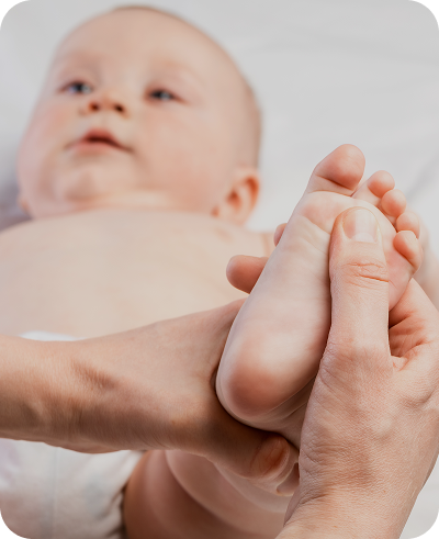Imagem de um bebê com uma mão de profissional massageando o pé