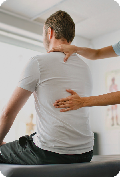 imagem de paciente sentado de costas e profissional apoiando uma das mãos no ombro e outra nas costas